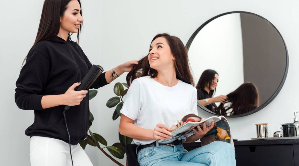 Happy woman hairdresser doing hairstyle for young girl